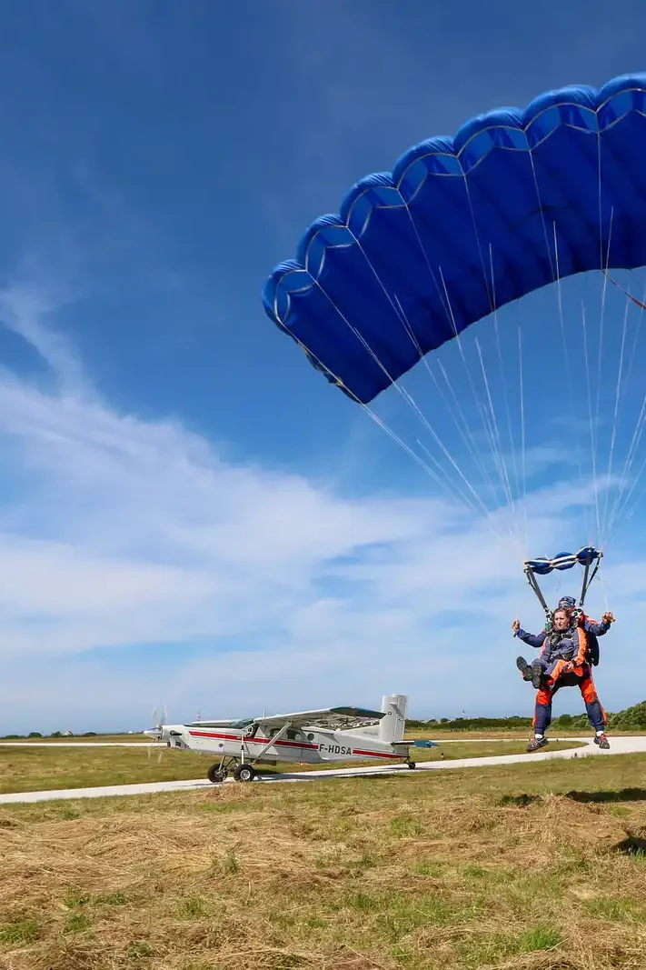 Atterrissage parachutiste tandem avec avion en arrière plan Atterrissage parachutiste tandem avec avion en arrière plan